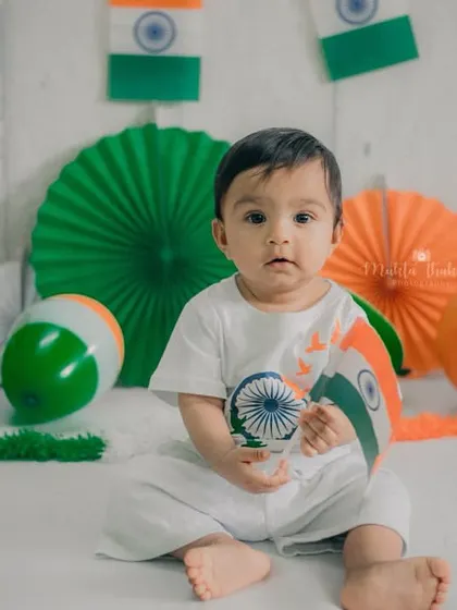 Holding a flag-themed prop, the baby looks at the camera with a calm and curious gaze. This is a simple yet beautiful portrait.