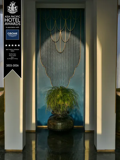 A bespoke art installation at Taj Devi Ratn, featuring a deep blue wall with delicate, cascading brass elements. This piece exemplifies our approach of creating unique, artistic focal points within our hospitality projects.