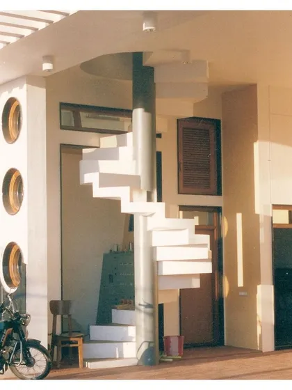This photo of the finished project showcases the play of light and shadow on the architectural forms, including the circular windows and the elegant white staircase.