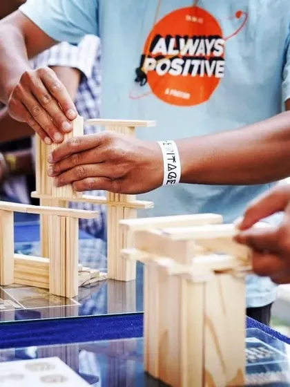 Two hands, one goal. This close-up shows the focused, hands-on nature of our activities. By working with tangible objects, teams develop a different kind of intelligence and problem-solving ability.