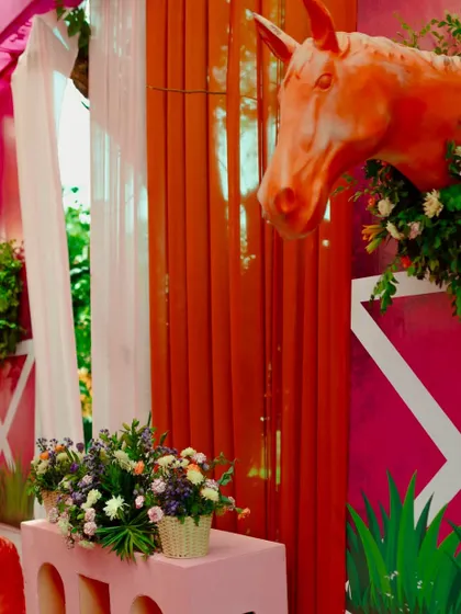 A detailed shot of the horse-themed decor, with a floral-wreathed horse sculpture against a vibrant pink and orange draped background.