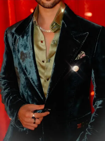 A detail shot of Jainam Vora's deep green velvet tuxedo, highlighting the fine buttonhole stitch and the rich texture of the velvet.