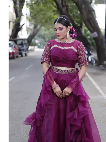 This wine-colored ruffled lehenga is a showstopper, perfect for a reception or cocktail party. The embroidered blouse adds a touch of traditional craftsmanship.