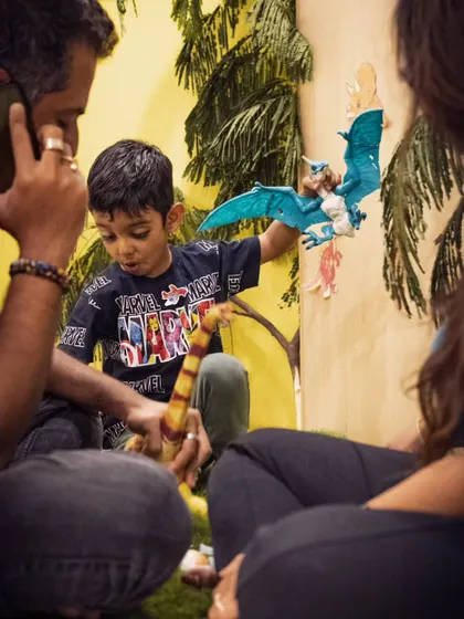 A candid shot of a child completely absorbed in playing with a dinosaur toy at an event. These are the quiet, authentic moments that often become the most treasured photographs.