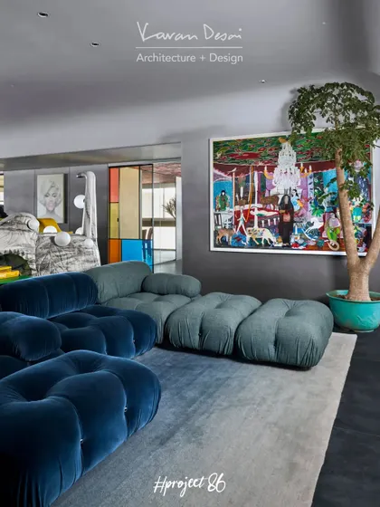 Another angle of the TV lounge, showing the large plant and colorful artwork that bring life to the space. The modular sofa allows for flexible seating arrangements, perfect for entertaining.