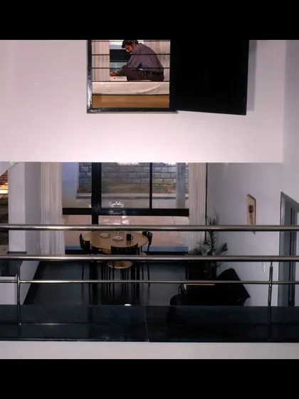 A view from the split-level study area into the double-height living space in the married students' housing. This design creates a sense of connection while maintaining distinct functional zones.