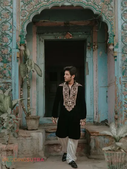 A stylish portrait of the groom against a rustic, textured doorway in Old Delhi. This shot highlights the unique character and charm of the location.