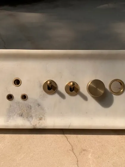 The final fabricated marble switch plate, with its subtle veining and cool, smooth surface. The brass elements provide a warm, tactile contrast.