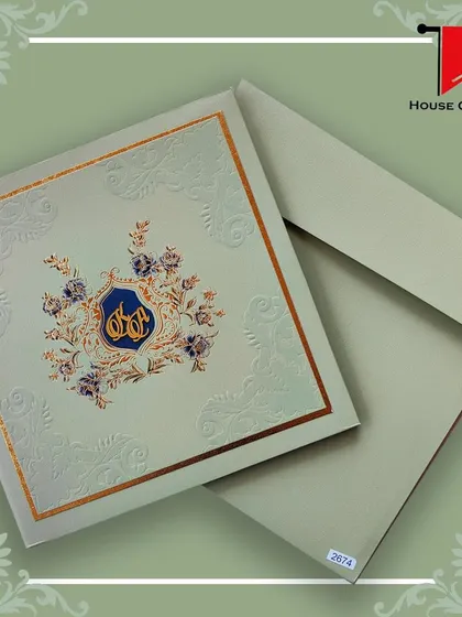 A sage green invitation with a custom blue and gold foil monogram. The embossed details add a tactile element to this luxurious design.