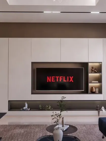 A close-up of the minimalistic TV unit at the Brigade Orchards villa, featuring clean lines, integrated shelving with backlighting, and a mix of closed and open storage.