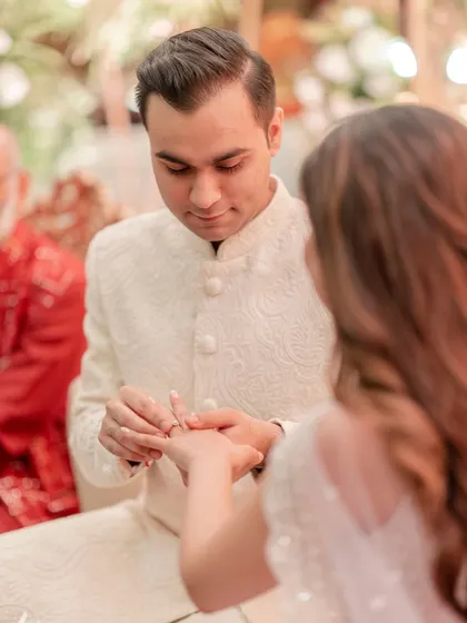 The groom gently places the engagement ring on his bride's finger, a classic and important shot.