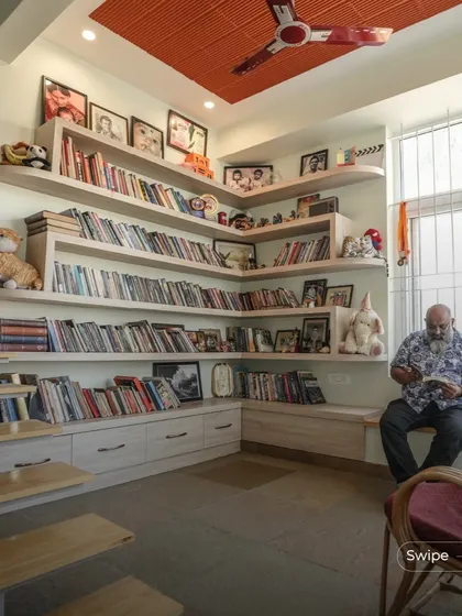 This cozy corner serves as a family library and reading nook. The custom-built shelves wrap around the corner, providing ample storage for books and memorabilia, while the built-in seating by the window is a perfect spot to read and relax.