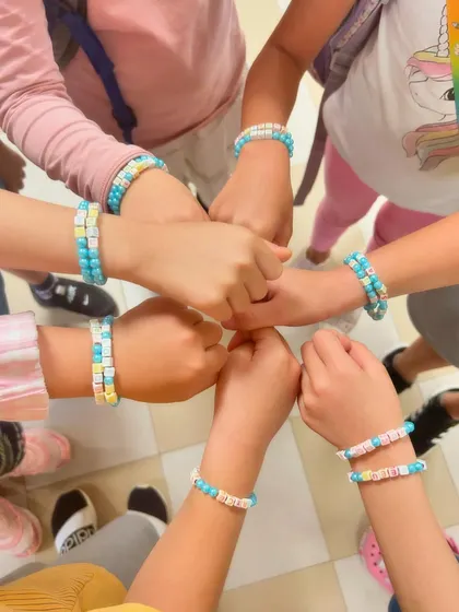 A group of friends showing off the matching bracelets they made. Crafting is a great way to build connections.