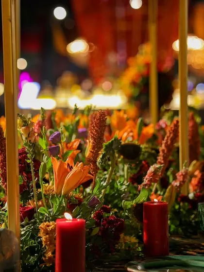 A close-up of a tablescape, featuring vibrant orange lilies and red candles. The warm candlelight creates an intimate and romantic ambiance for the dinner celebration.