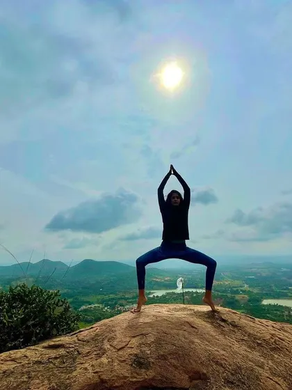 Embracing the powerful energy of Kaliasana, or goddess pose, on a hilltop overlooking a vast landscape. This pose connects you to your inner strength.