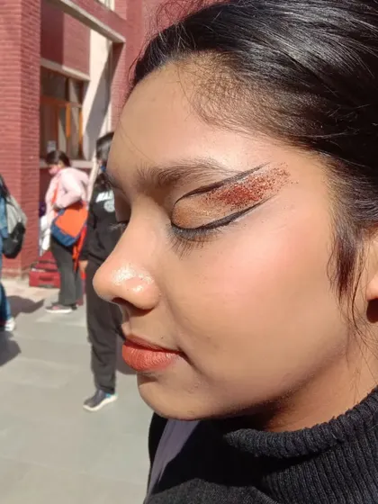 A glittery winged eyeliner look using copper-toned glitter. This is a great way to elevate your makeup for a special occasion.