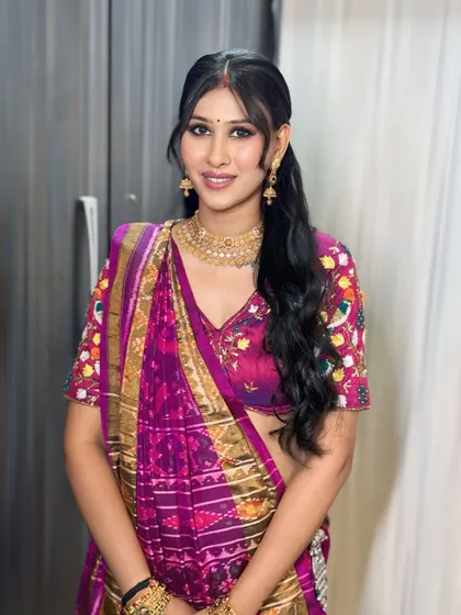 A modern take on a traditional look. This client is wearing a vibrant purple bandhani saree with a chic ponytail and glowing makeup.