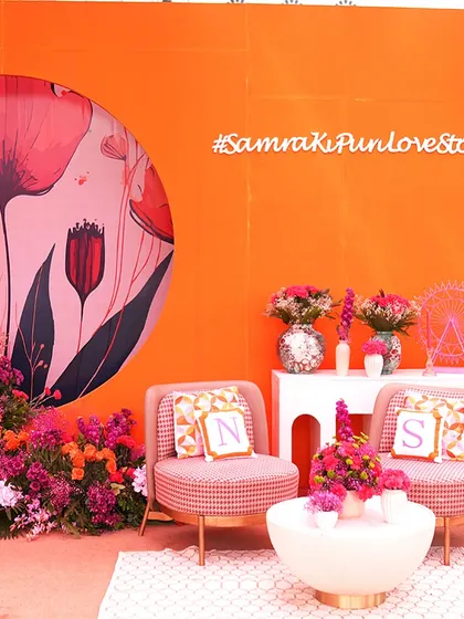 A personalized seating nook for the couple, complete with custom initialed pillows and a vibrant floral backdrop. Every detail is designed to tell their unique love story.