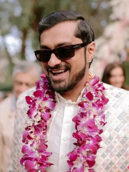 A close-up of the happy groom, wearing a beautiful orchid garland, enjoying his Mehendi ceremony.