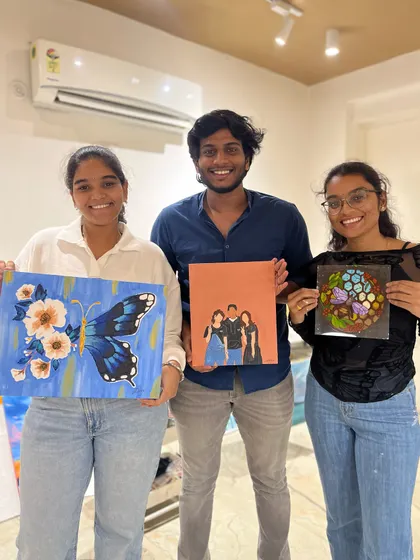 A group of three young adults with their impressive paintings, showcasing a variety of styles from portraiture to abstract.