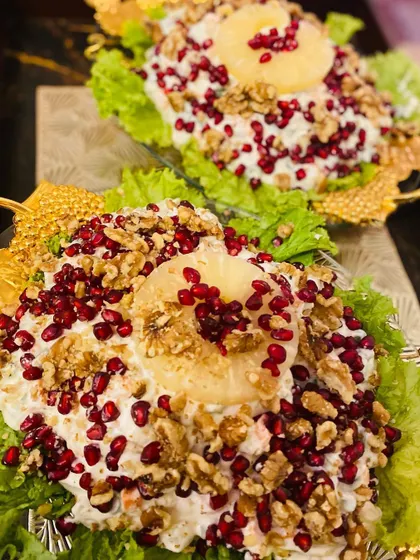 My Russian Salad presented in elegant leaf-shaped bowls, topped with pineapple rings, pomegranate jewels, and walnuts.