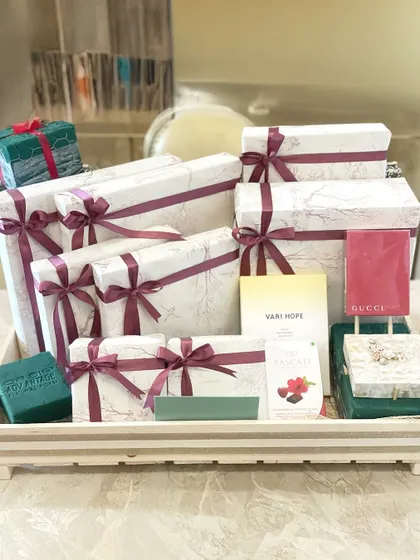 A tray full of beautifully wrapped gifts for the bride, featuring marble-print boxes with burgundy ribbons. This hamper also includes luxury items from Gucci.