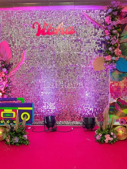 The main photo stage with a shimmering silver sequin backdrop, a colorful boombox prop, and vibrant floral arrangements.