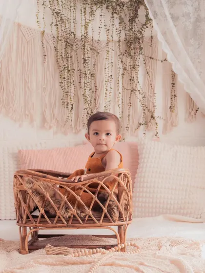 A close-up of the birthday boy in the rattan bassinet. The soft, neutral colors of the bohemian set are perfect for a calm and beautiful milestone session.