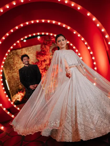 The bride and groom make their way through the glowing red vortex, a dramatic entrance for their unforgettable Sangeet night.