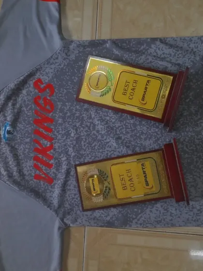 Excellence in coaching is the foundation of our success. Here are two "Best Coach" awards displayed proudly on a Vikings jersey, proving that our leadership is among the best.