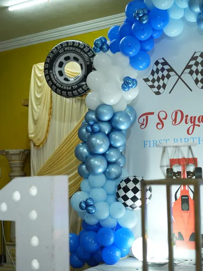 We incorporated fun elements like a real tire into the balloon arch for this racing-themed birthday. The mix of blue and white balloons with checkered flags completes the look.