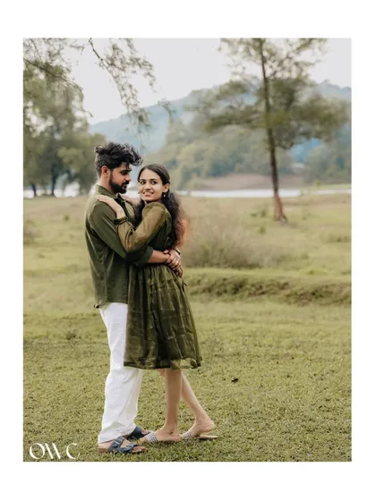 A sweet and simple couple portrait in a field, with a lake in the background, capturing a moment of quiet connection.