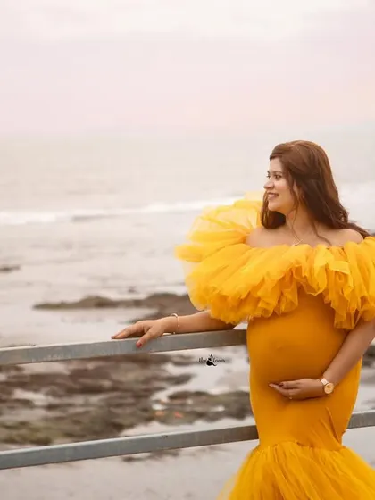 A solo portrait by the sea. The mother-to-be looks out at the horizon, creating a photo that feels hopeful and full of dreams for the future.