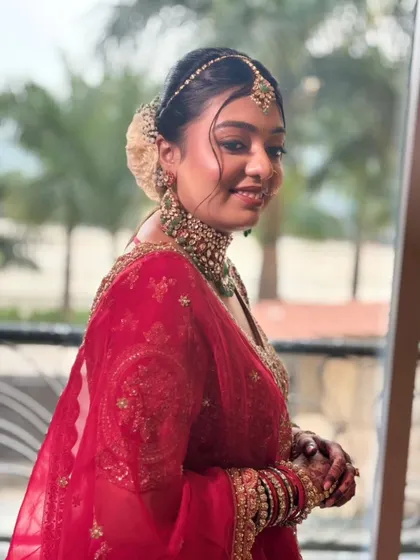 Another beautiful shot by the window, capturing her happy and radiant expression. The hairstyle with a simple floral touch completes this elegant bridal look.