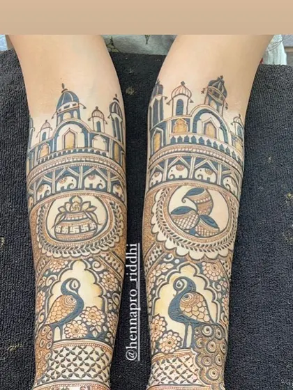 A look at the top and bottom of a bridal design. This shows the grand palace architecture at the elbows and the detailed peacock work further down the arm, demonstrating the flow of the design.