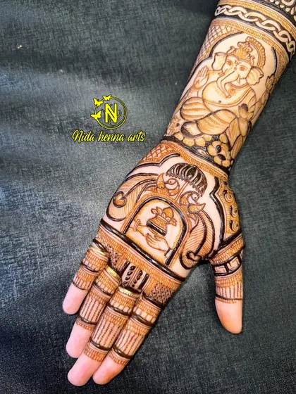 This designer mehandi combines a portrait of Lord Ganesha on the arm with a peacock and kalash motif on the palm. It's a beautiful blend of spirituality and tradition.