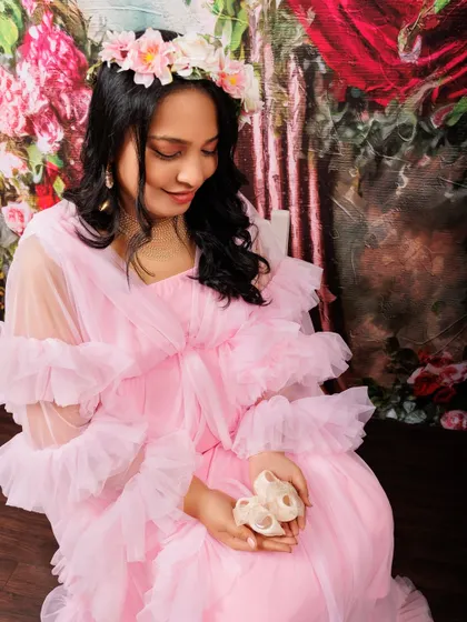 It’s the little details that hold so much meaning. Here, an expecting mother in a soft pink gown holds a tiny pair of baby shoes, a sweet symbol of the little one on the way. I love incorporating personal or symbolic props to make your maternity photos even more special.