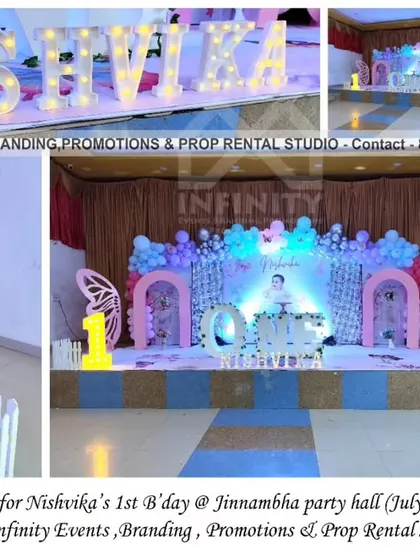 A dreamy butterfly theme for a first birthday at Jinnambha Party Hall. The large stage setup includes a sequin wall, 3D semi-arch backdrops, a "ONE" table, and a pastel balloon garland, creating a grand and whimsical celebration.
