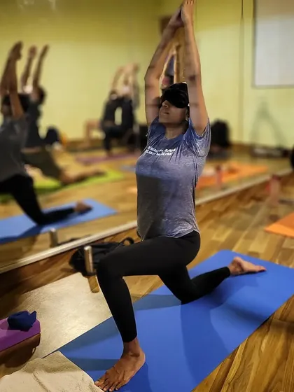 A student practicing Anjaneyasana, or Low Lunge, while blindfolded. This practice heightens body awareness and focus.