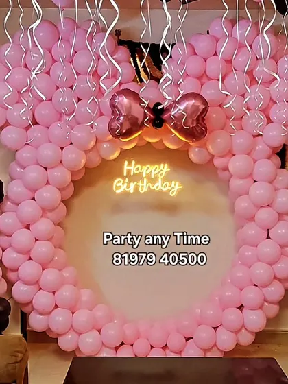 A creative Minnie Mouse decoration featuring a large balloon frame shaped like Minnie's head, perfect for a unique photo booth at home.