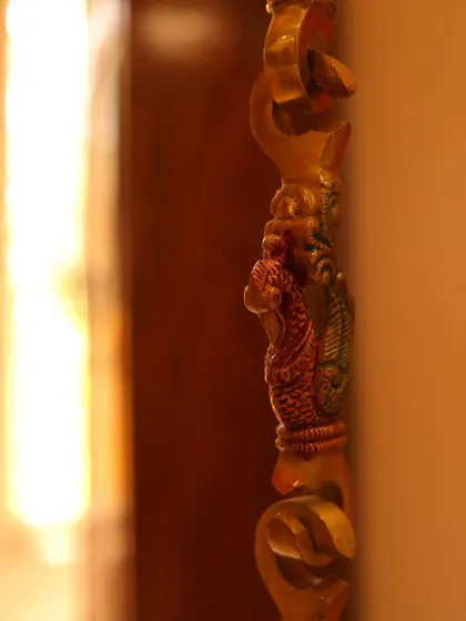 Another detailed shot of the ornate brass swing chain, highlighting the intricate peacock motif.