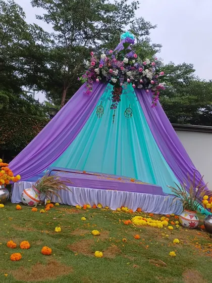A wider view of the outdoor Mehendi teepee setup, decorated with marigolds and other props.