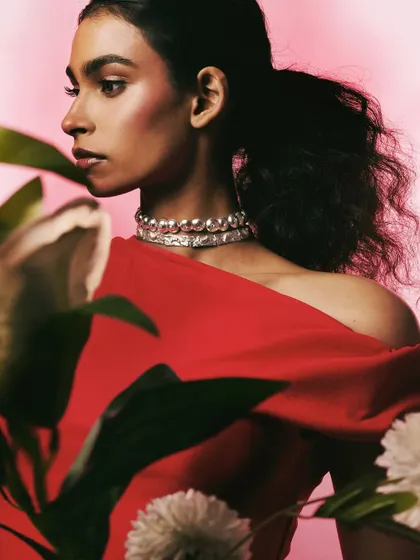 A romantic and soft-focused shot for Batoki.art, with the model in a red dress framed by flowers. The image highlights a silver choker, creating a mood perfect for a Valentine's campaign.