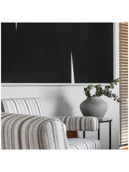 Detail of the seating area in the director's cabin. The striped armchair, minimalist side table, and bold black artwork come together to create a composition of texture, form, and contrast.