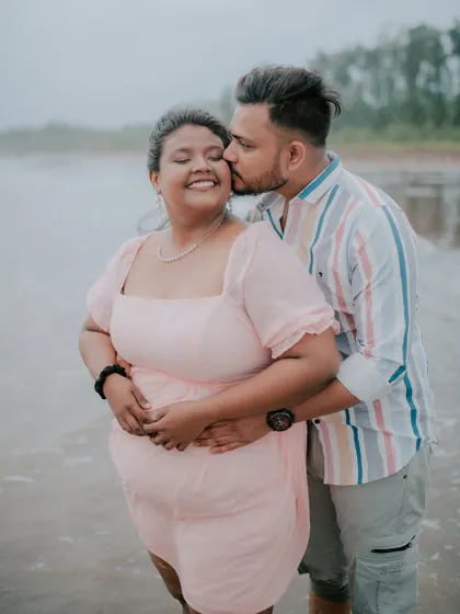 A sweet kiss on the cheek as the waves roll in during a beach pre-wedding shoot.