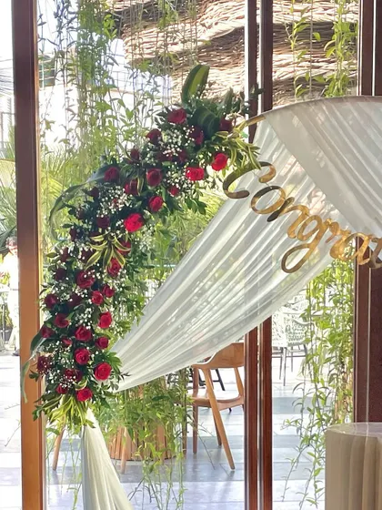 A close-up of the floral arrangement on the circular arch, showcasing the deep red roses and delicate baby's breath.