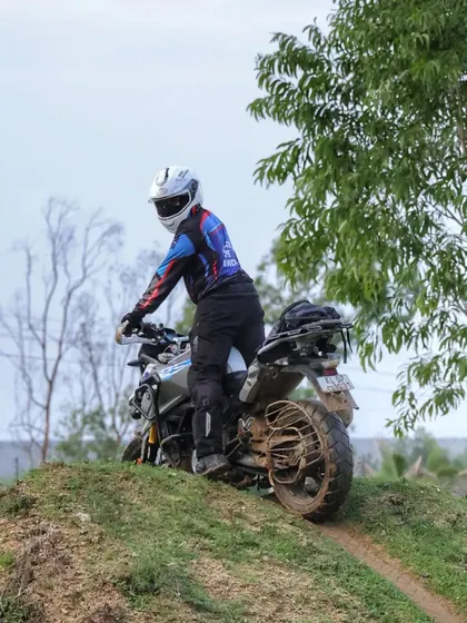 A rider in full gear navigates a grassy, uneven slope. Our Level 1 training helps you build the core confidence and balance needed for exactly these kinds of off-road challenges.