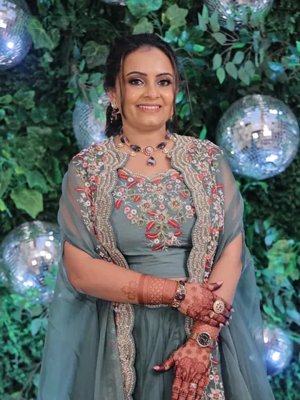 Soft glam with warm coral hues for an engagement party. This look features a defined smokey eye and a simple twisted hairstyle, set against a fun disco ball backdrop.