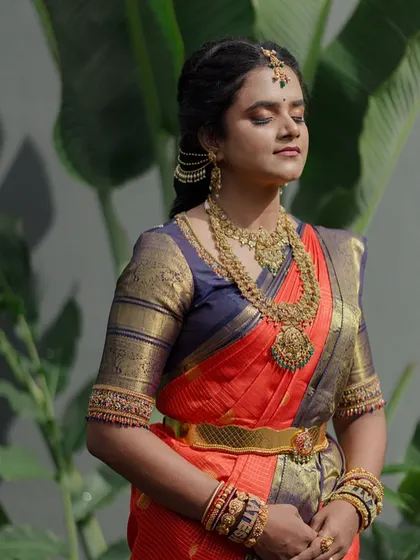 A serene portrait of the bride with her eyes closed. The focus is on the beautiful texture of her saree and the intricate details of her jewelry.
