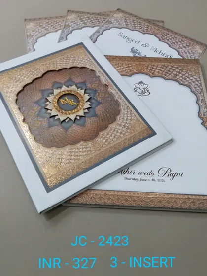A premium boxed invitation with an intricate, multi-layered mandala design and a custom monogram. The white and bronze color scheme is elegant, and the set includes three inserts for your events.